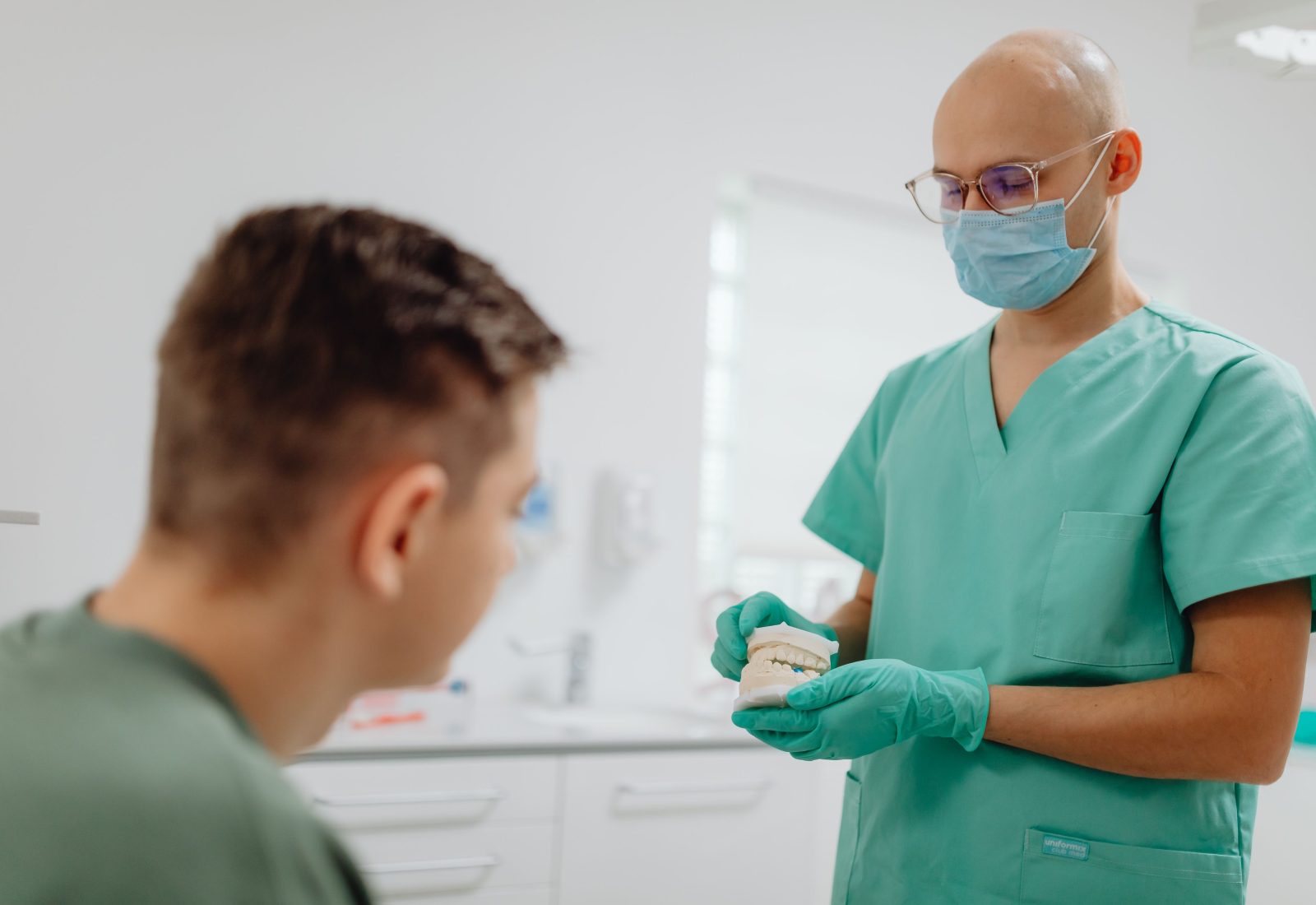 Zahnarzt erklärt einer Patientin anhand eines Zahnmodells die Behandlung